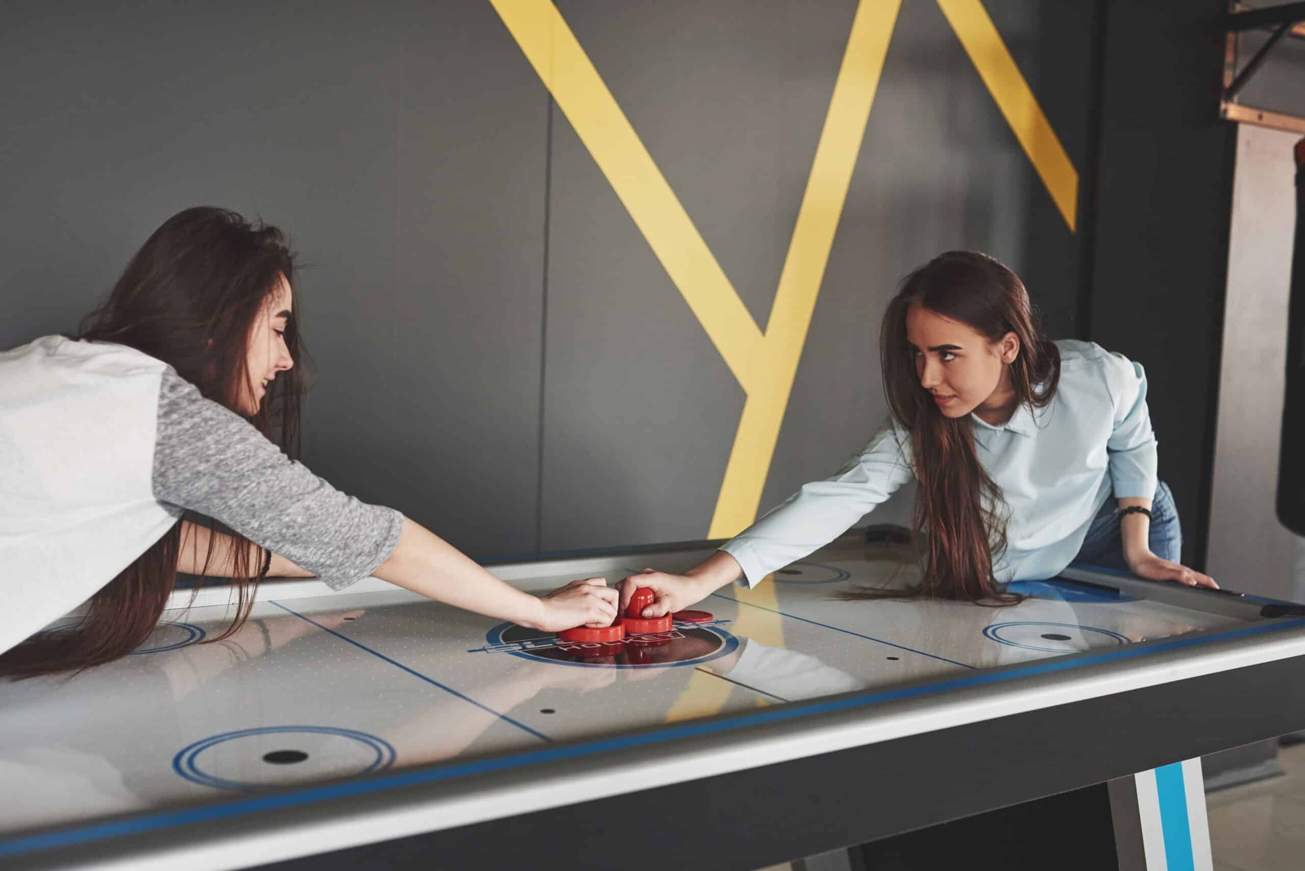 two-beautiful-twin-girls-play-air-hockey-game-roomand-have-fun-1