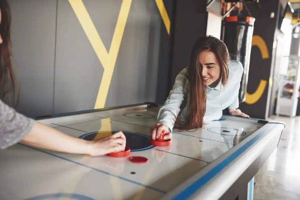 two-beautiful-twin-girls-play-air-hockey-game-roomand-have-fun